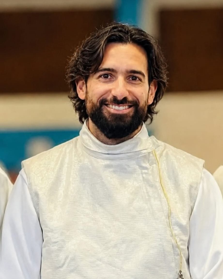 Armand Genest, souriant, en tenue d'escrime